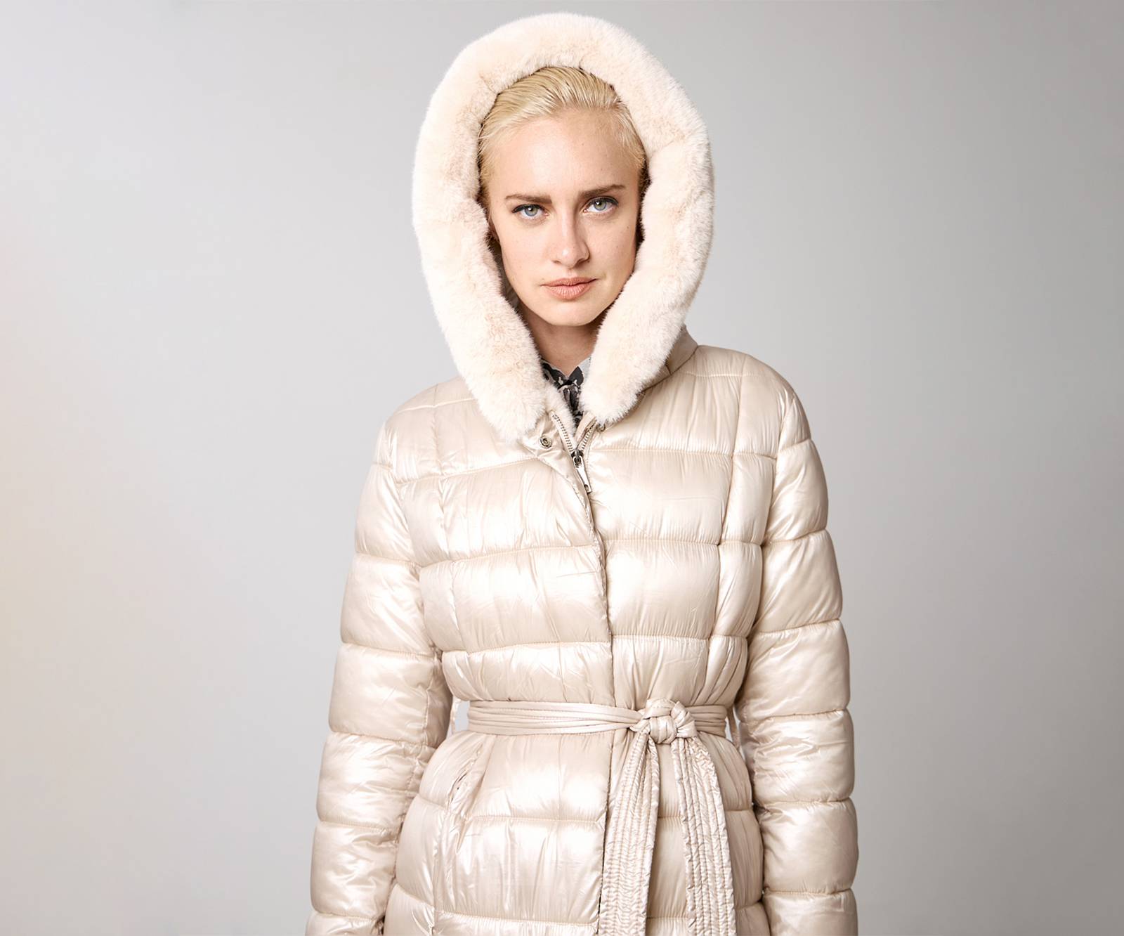 Long puffer jacket with a hood with faux fur details in beige in London, UK